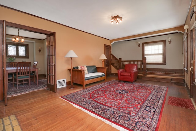 sitting room with hardwood / wood-style floors, ornamental molding, and a chandelier