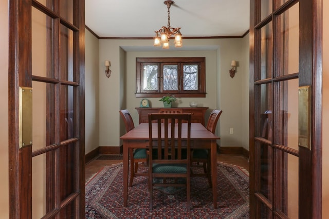 dining space with an inviting chandelier, ornamental molding, and french doors