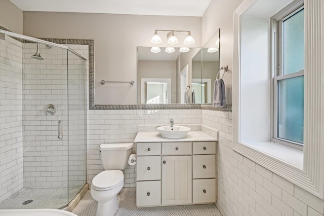 bathroom with tile patterned floors, a healthy amount of sunlight, a shower with shower door, and tile walls