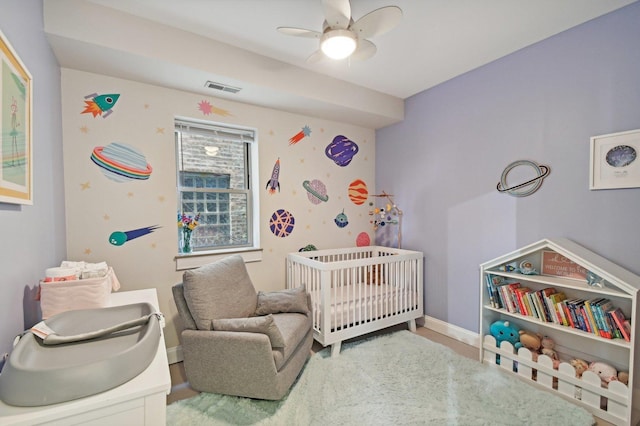 bedroom with ceiling fan and a nursery area