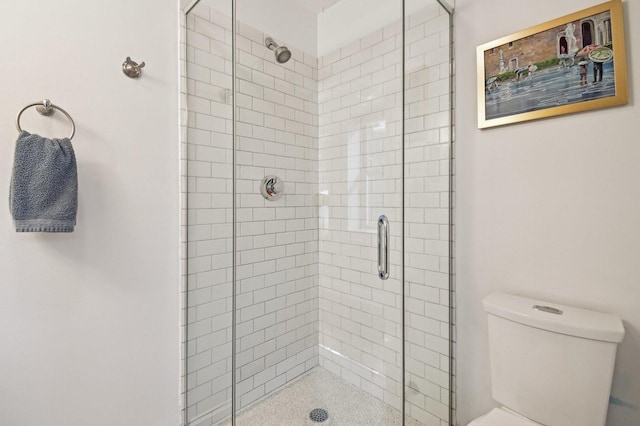 bathroom featuring toilet and a shower with shower door