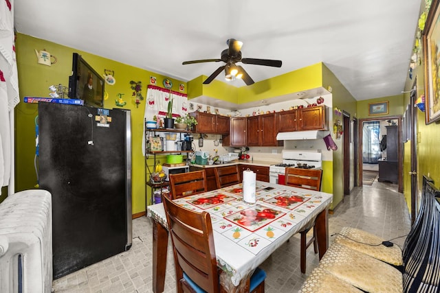 kitchen featuring stainless steel refrigerator, ceiling fan, white range with gas cooktop, and radiator heating unit