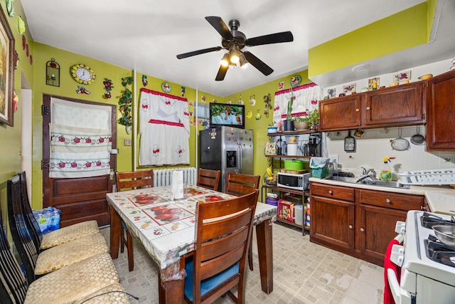 kitchen featuring stainless steel appliances, radiator, tasteful backsplash, ceiling fan, and sink