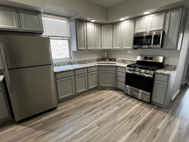 kitchen featuring sink, stainless steel appliances, light wood-type flooring, and gray cabinets