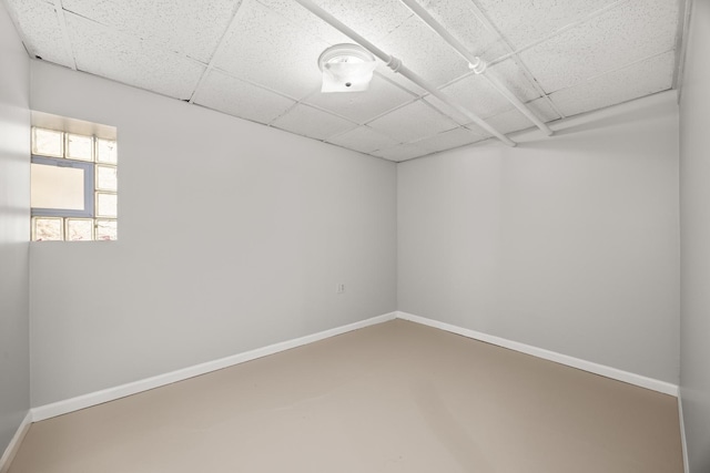 spare room featuring a paneled ceiling and concrete floors