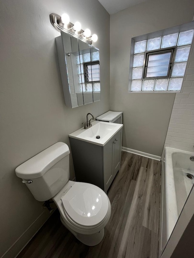 bathroom featuring toilet, vanity, hardwood / wood-style floors, and a bathtub