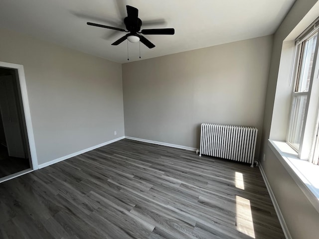 spare room with ceiling fan, dark wood-type flooring, and radiator