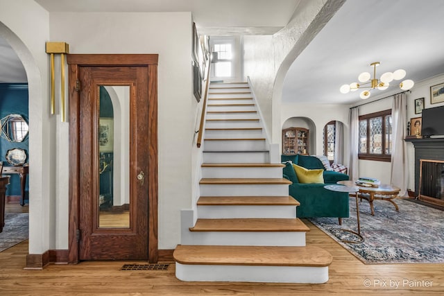 staircase featuring wood-type flooring and a chandelier