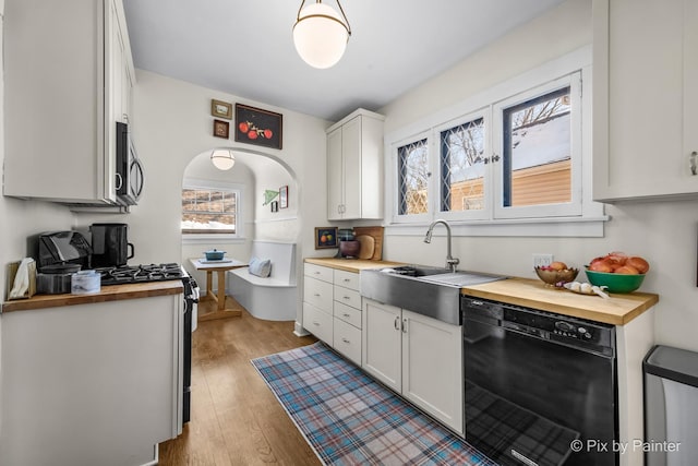 kitchen with sink, white cabinets, butcher block countertops, a wealth of natural light, and black appliances