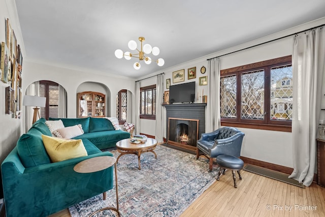 living room with a chandelier, crown molding, and wood-type flooring