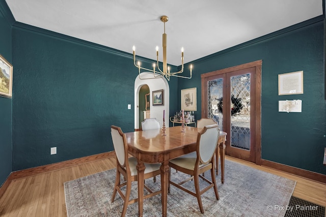 dining area with light hardwood / wood-style floors, a chandelier, french doors, and ornamental molding