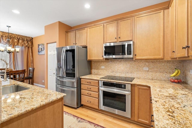 kitchen featuring light hardwood / wood-style floors, light stone countertops, appliances with stainless steel finishes, and a chandelier