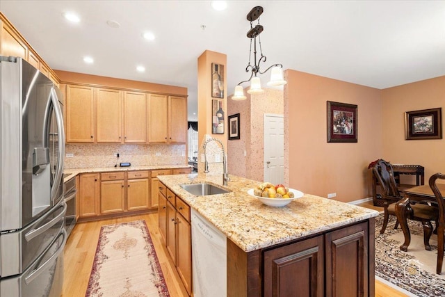 kitchen featuring pendant lighting, sink, stainless steel fridge, white dishwasher, and light hardwood / wood-style flooring