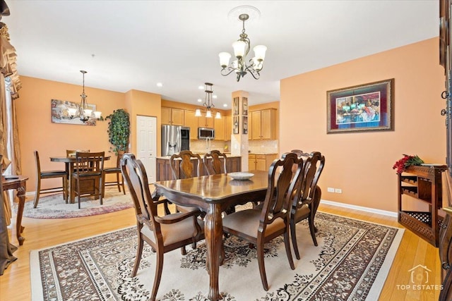 dining space with light wood-type flooring and an inviting chandelier