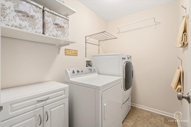 clothes washing area with cabinets and washer and clothes dryer