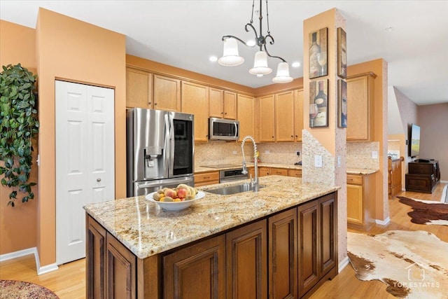 kitchen featuring an inviting chandelier, light hardwood / wood-style floors, appliances with stainless steel finishes, hanging light fixtures, and light stone counters