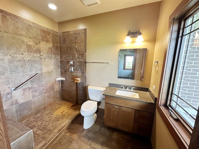 bathroom featuring vanity, toilet, and a tile shower