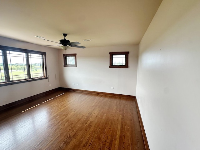 unfurnished room featuring ceiling fan, plenty of natural light, and dark wood-type flooring