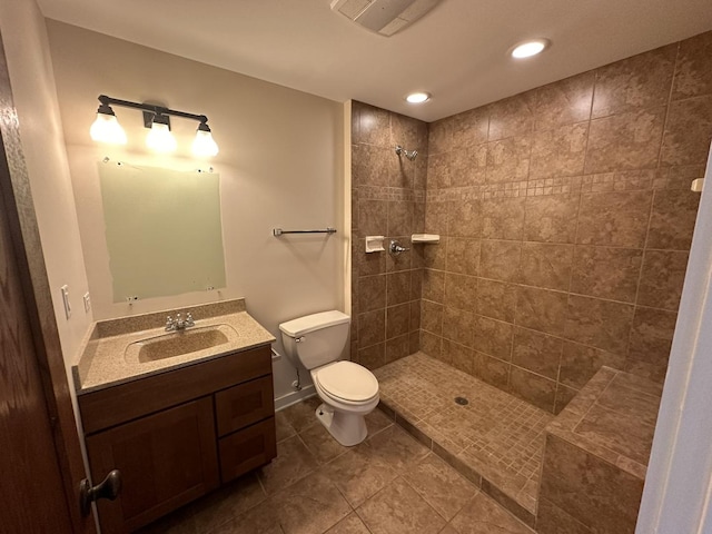 bathroom with tiled shower, tile patterned floors, vanity, and toilet