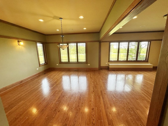 empty room with a chandelier, light hardwood / wood-style floors, and crown molding