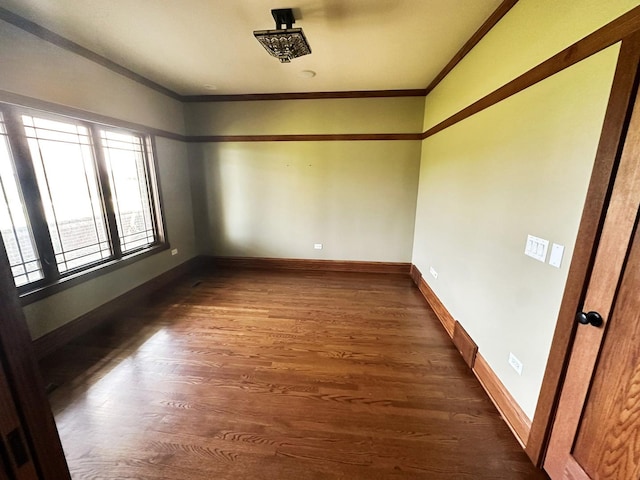 empty room featuring crown molding and dark wood-type flooring