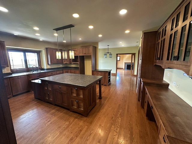 kitchen with hardwood / wood-style flooring, a kitchen island, sink, and hanging light fixtures