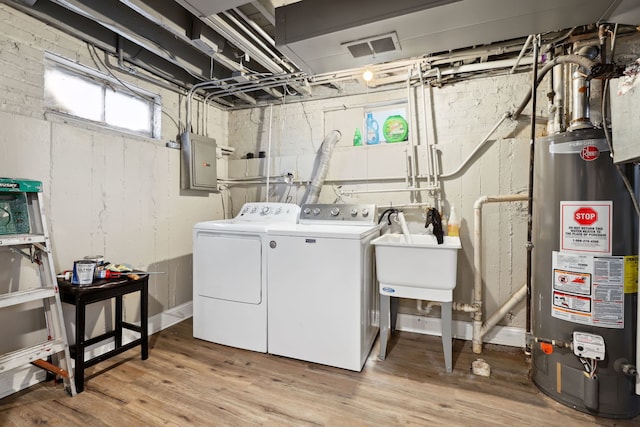 washroom with gas water heater, sink, washer and clothes dryer, light hardwood / wood-style flooring, and electric panel