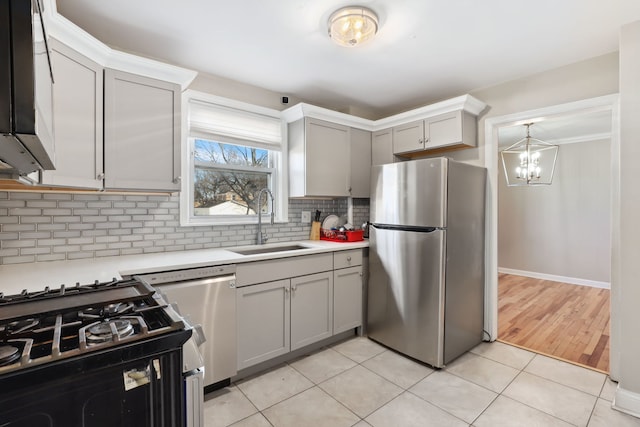 kitchen with sink, tasteful backsplash, gray cabinetry, light tile patterned floors, and stainless steel appliances