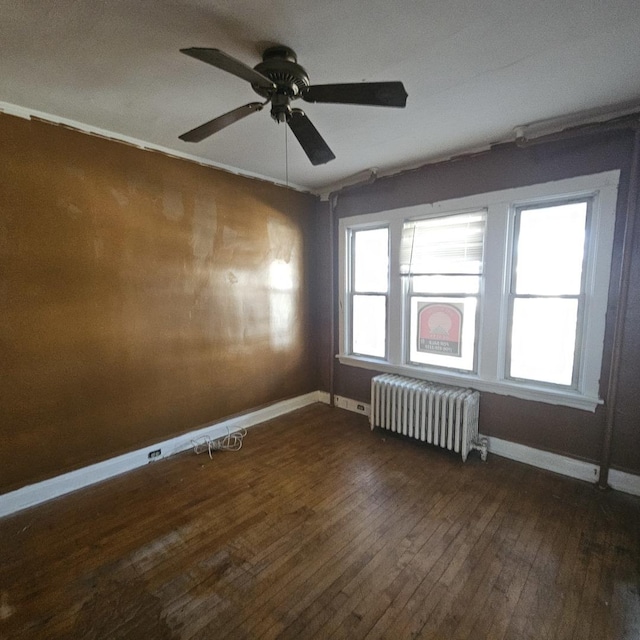 unfurnished room featuring ceiling fan, radiator heating unit, and dark wood-type flooring