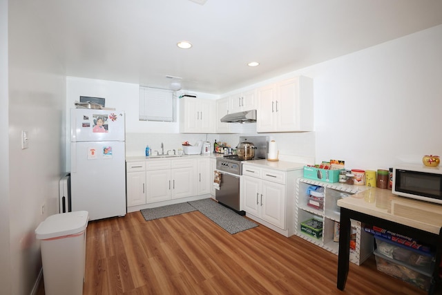 kitchen with white refrigerator, wood-type flooring, white cabinetry, and high end range