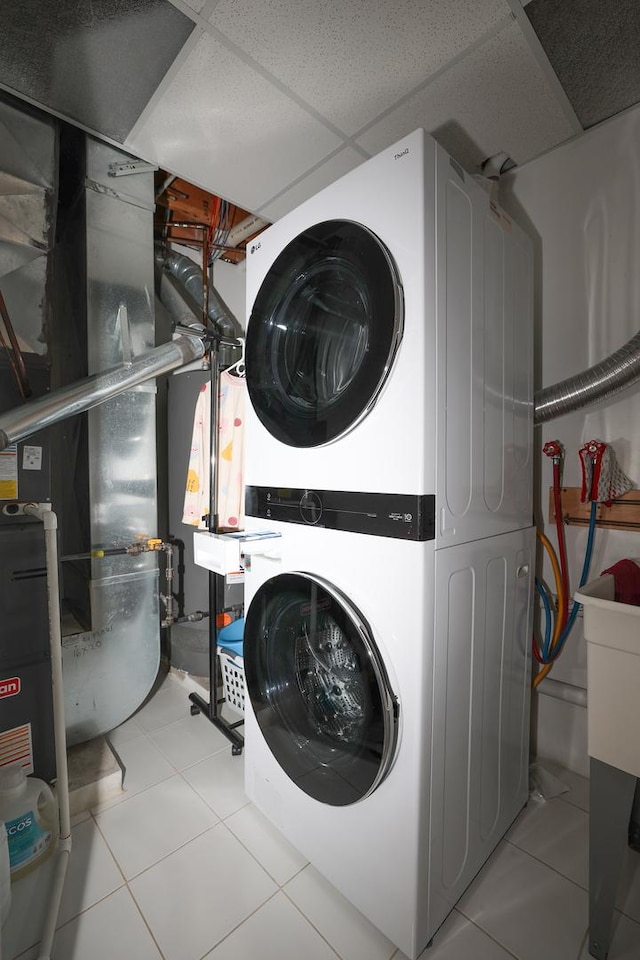 laundry room with heating unit, stacked washing maching and dryer, and light tile patterned floors