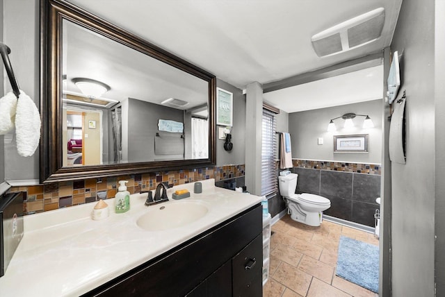 bathroom featuring toilet, tile patterned floors, tasteful backsplash, and vanity