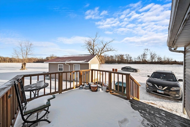 snow covered deck with a garage and an outbuilding