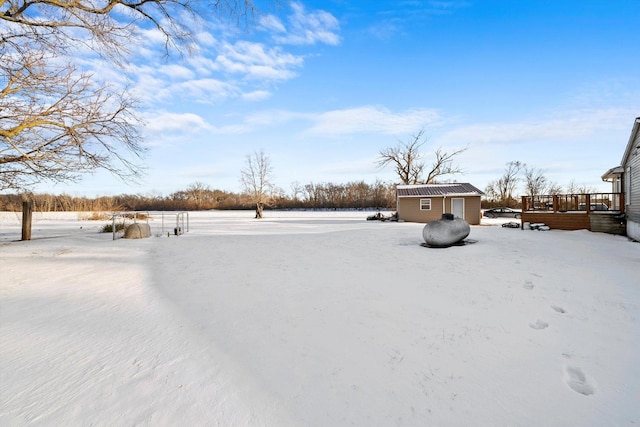 yard covered in snow with a wooden deck and an outbuilding