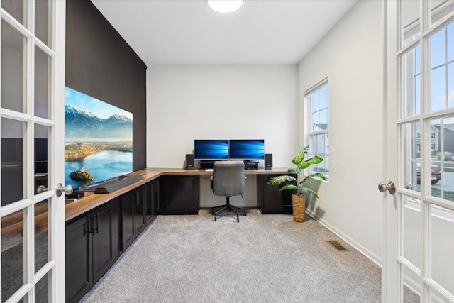 office space featuring light carpet, french doors, and built in desk