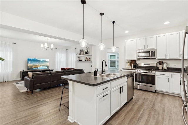 kitchen featuring appliances with stainless steel finishes, decorative light fixtures, white cabinetry, and sink