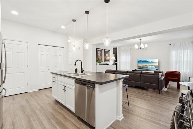 kitchen with sink, dishwasher, white cabinetry, hanging light fixtures, and an island with sink