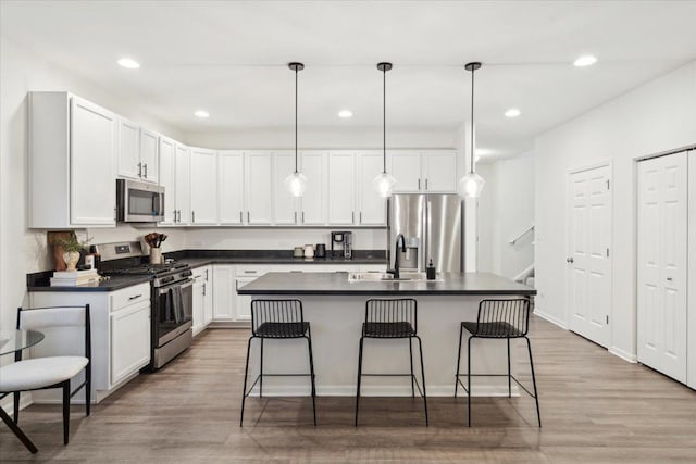 kitchen with appliances with stainless steel finishes, hanging light fixtures, a breakfast bar area, and sink