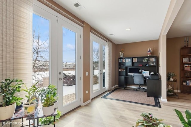 office featuring visible vents, baseboards, built in desk, french doors, and wood finished floors