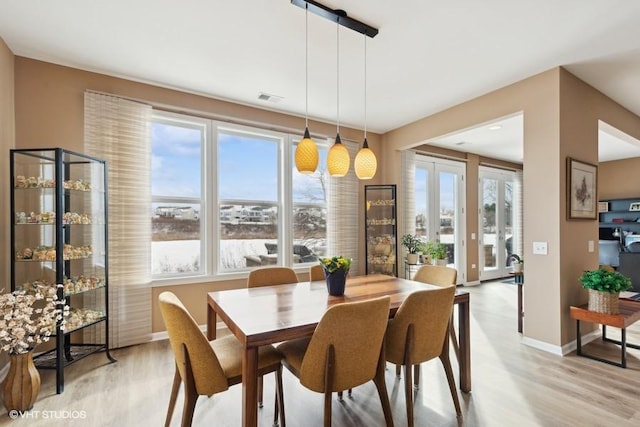 dining room featuring visible vents, baseboards, french doors, and light wood finished floors