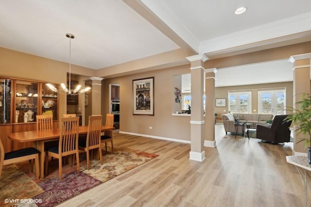 dining space with decorative columns, baseboards, a notable chandelier, and wood finished floors