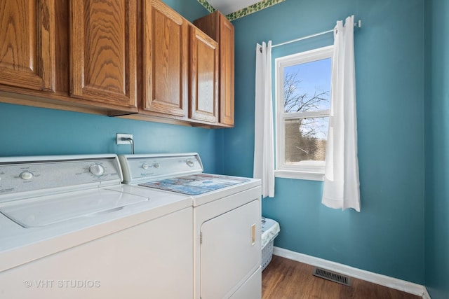 laundry area featuring washer and clothes dryer, dark wood-type flooring, and cabinets