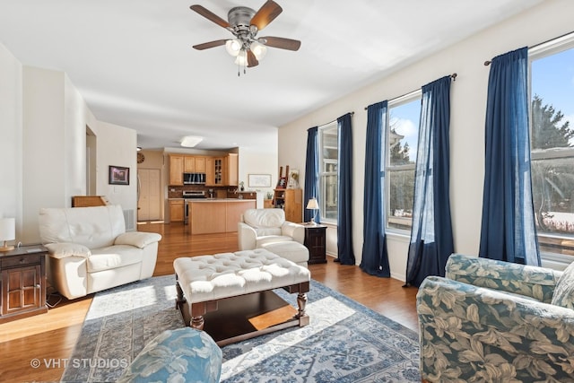 living room featuring ceiling fan, plenty of natural light, and light hardwood / wood-style flooring