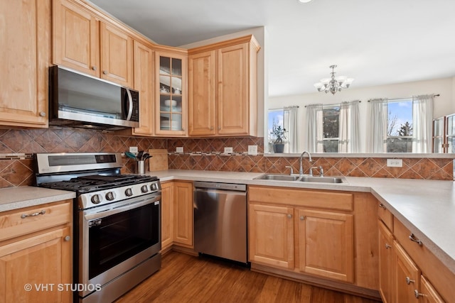 kitchen featuring light hardwood / wood-style floors, stainless steel appliances, decorative backsplash, a chandelier, and sink