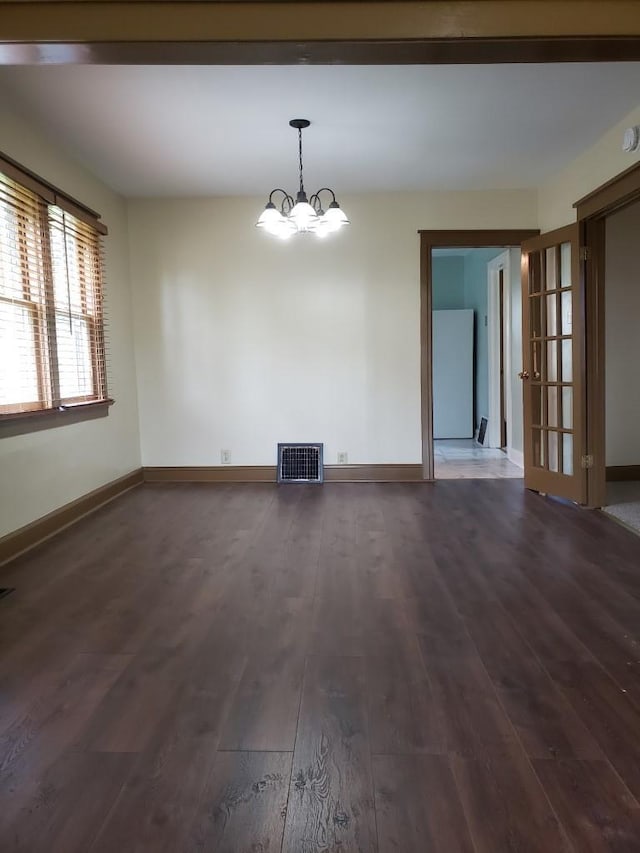 spare room featuring dark hardwood / wood-style floors and a chandelier