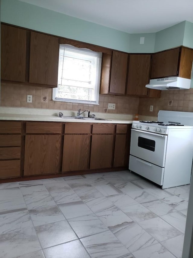 kitchen featuring white range with gas stovetop, backsplash, and sink