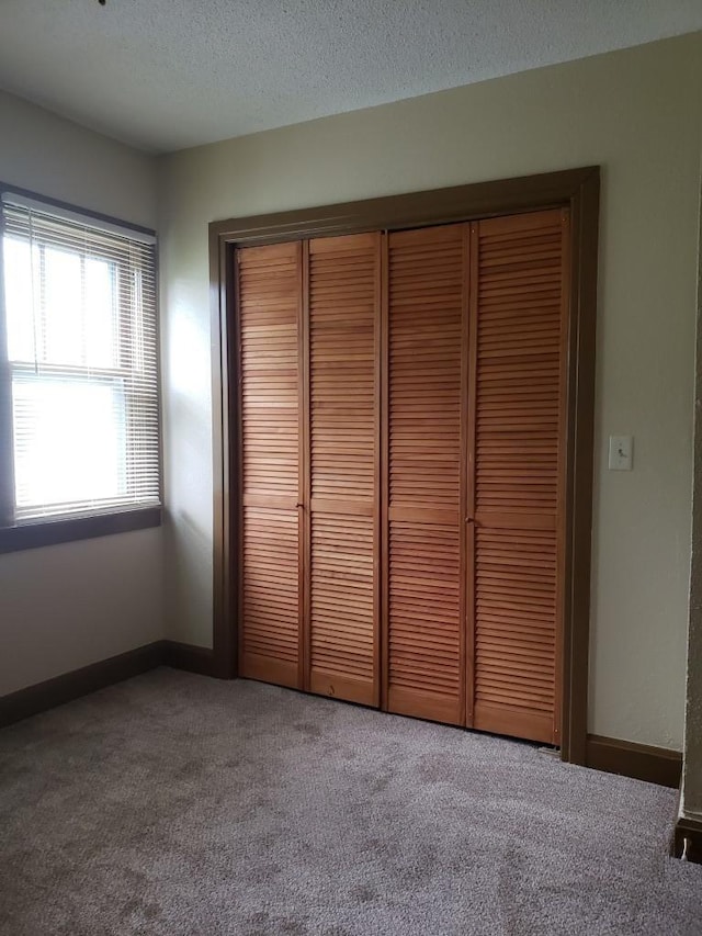 unfurnished bedroom featuring a closet, carpet, and a textured ceiling