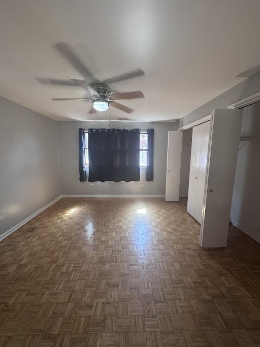 unfurnished bedroom with two closets, ceiling fan, and dark parquet floors