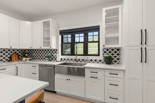 kitchen with white cabinetry, stainless steel dishwasher, sink, and tasteful backsplash