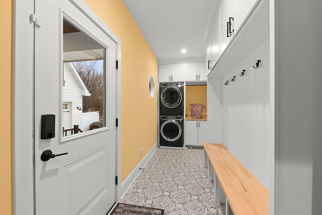 clothes washing area with cabinets and stacked washer / dryer